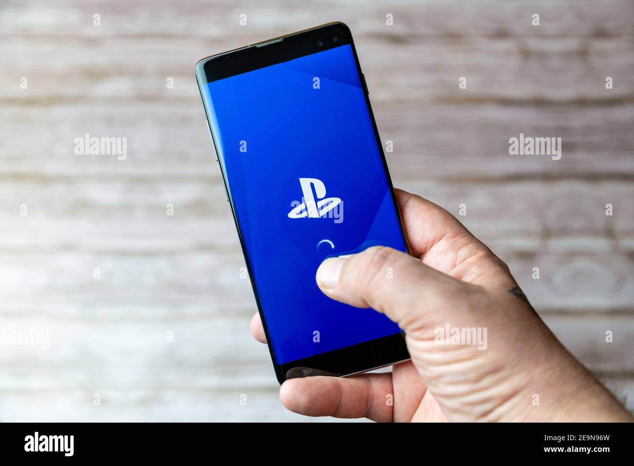 Ein Mobiltelefon oder Mobiltelefon, das/das gehalten wird, zeigt das an Die PlayStation Mobile-App wird auf dem Bildschirm geöffnet Stockfoto