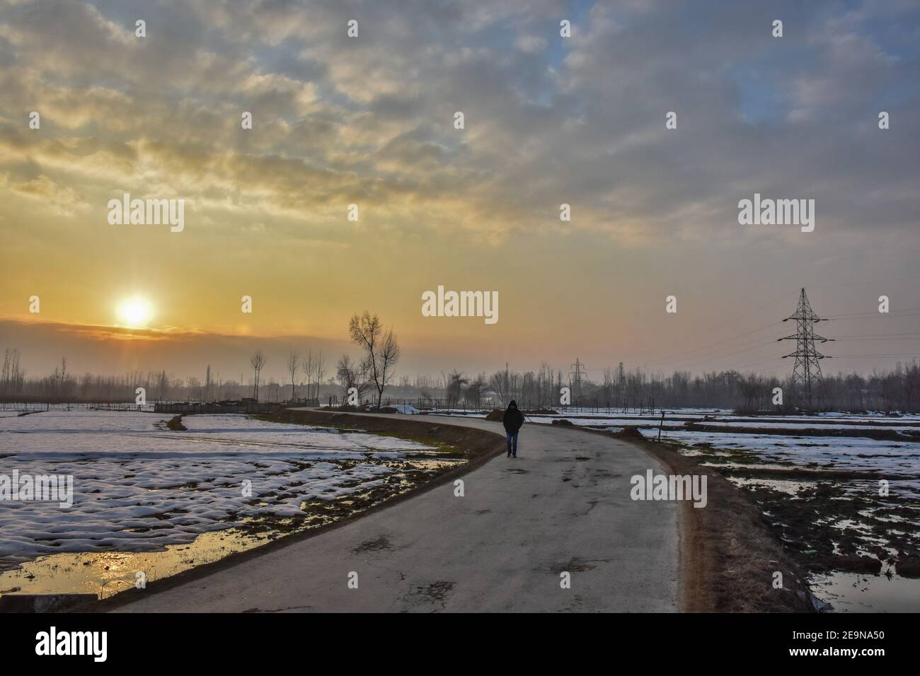 Ein Mann geht entlang der Straße während des Sonnenuntergangs in Srinagar.Wetter über der Stadt Srinagar hat sich verbessert, nachdem Kaschmir frischen Schneefall erhielt. Die Mindesttemperatur blieb über dem Gefrierpunkt in der Stadt Srinagar, da das Wetterbüro das trockene Wetter für die nächsten sieben Tage prognostizierte. Stockfoto