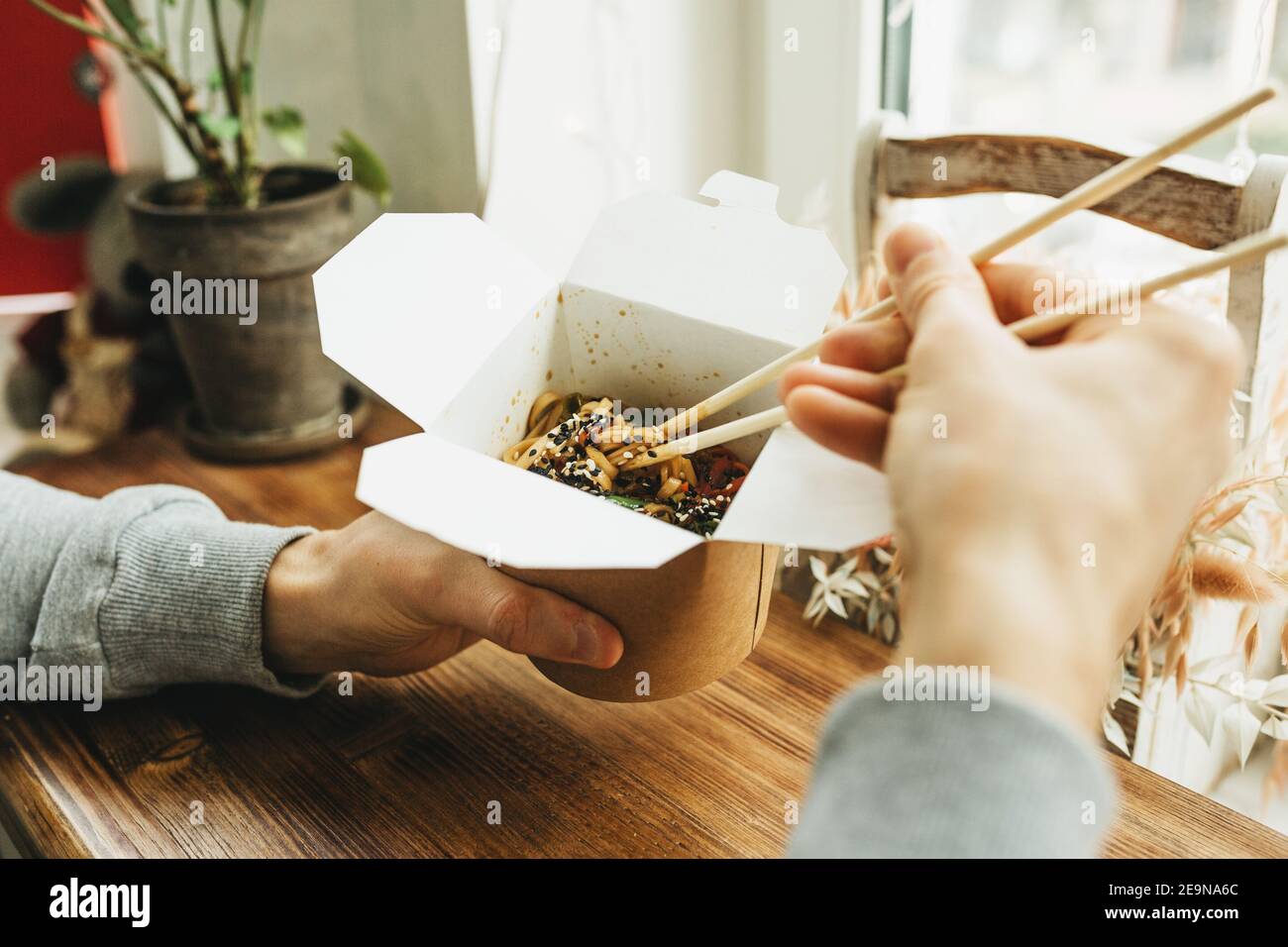 Nahaufnahme von Nudeln in einer Schachtel. Essen zum Mitnehmen. Person isst Nahrung mit Essstäbchen. Stockfoto