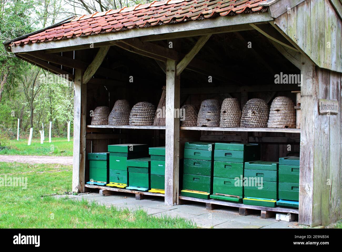 Rekonstruierte altmodische Bienenscheune für die Imkerei. Es gibt zwei Reihen von Bienenstöcken in. Körbe und Boxen. Bienenspinner. Stockfoto