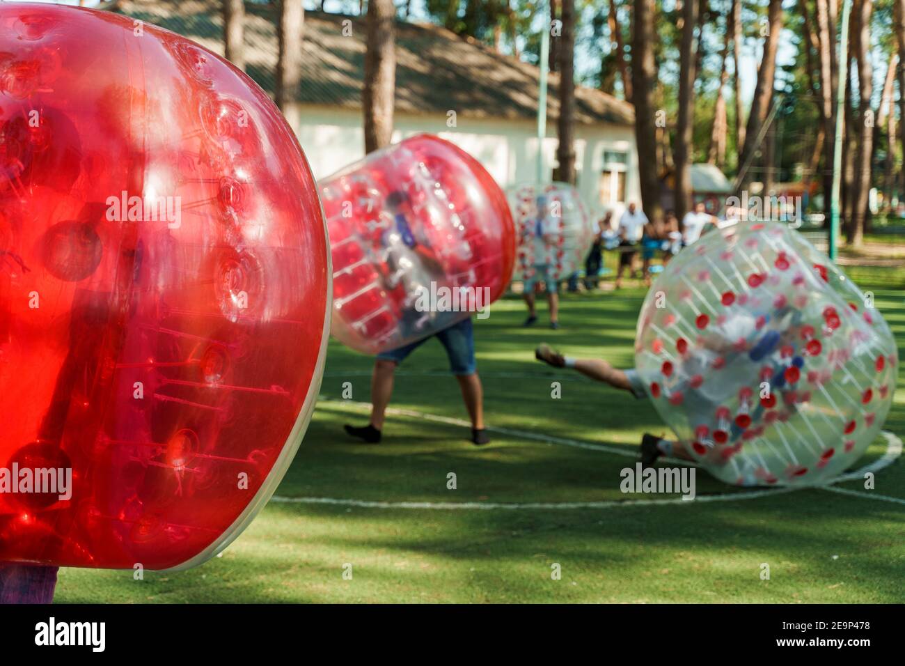 Bubble Fußball Sport Spiel. Fußballspieler spielen Bumperball auf dem grünen Feld. Teambildung. Mann in Blase Ballon laufen. Stockfoto