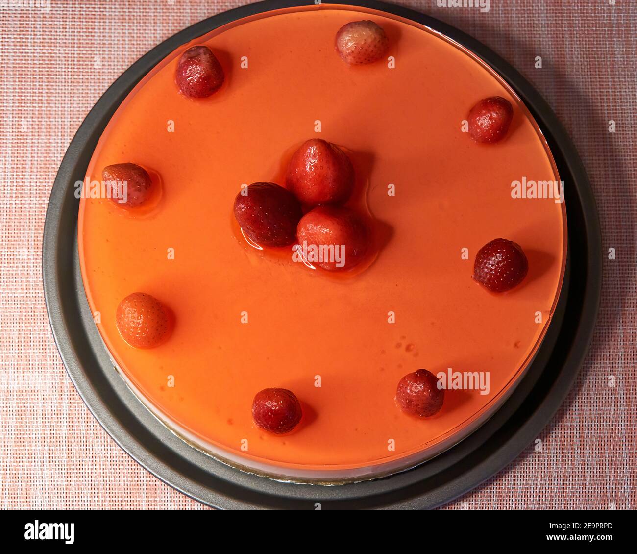 Draufsicht auf hausgemachten Käsekuchen mit Erdbeergelee, natürlichen Erdbeeren und Erdbeersirup Stockfoto