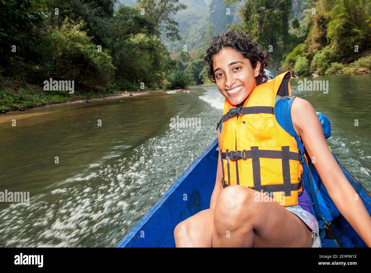 Junge Frau genießt eine Fahrt auf einem langen Boot In Laos Stockfoto