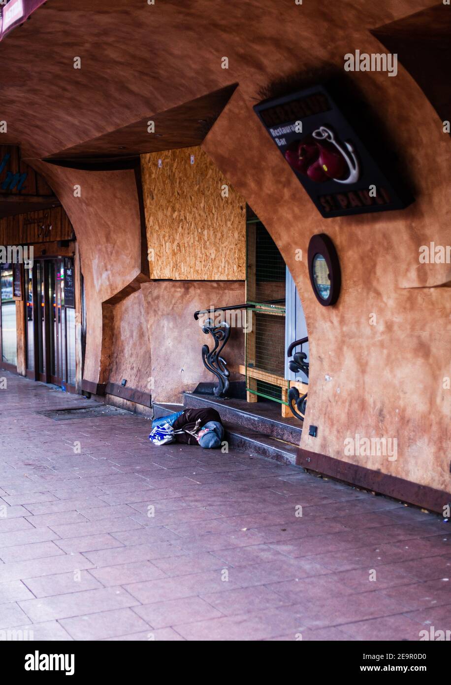Obdachlose Person, die vor der Haustür eines geschlossenen Clubs schläft Während der Corona-Sperre Stockfoto