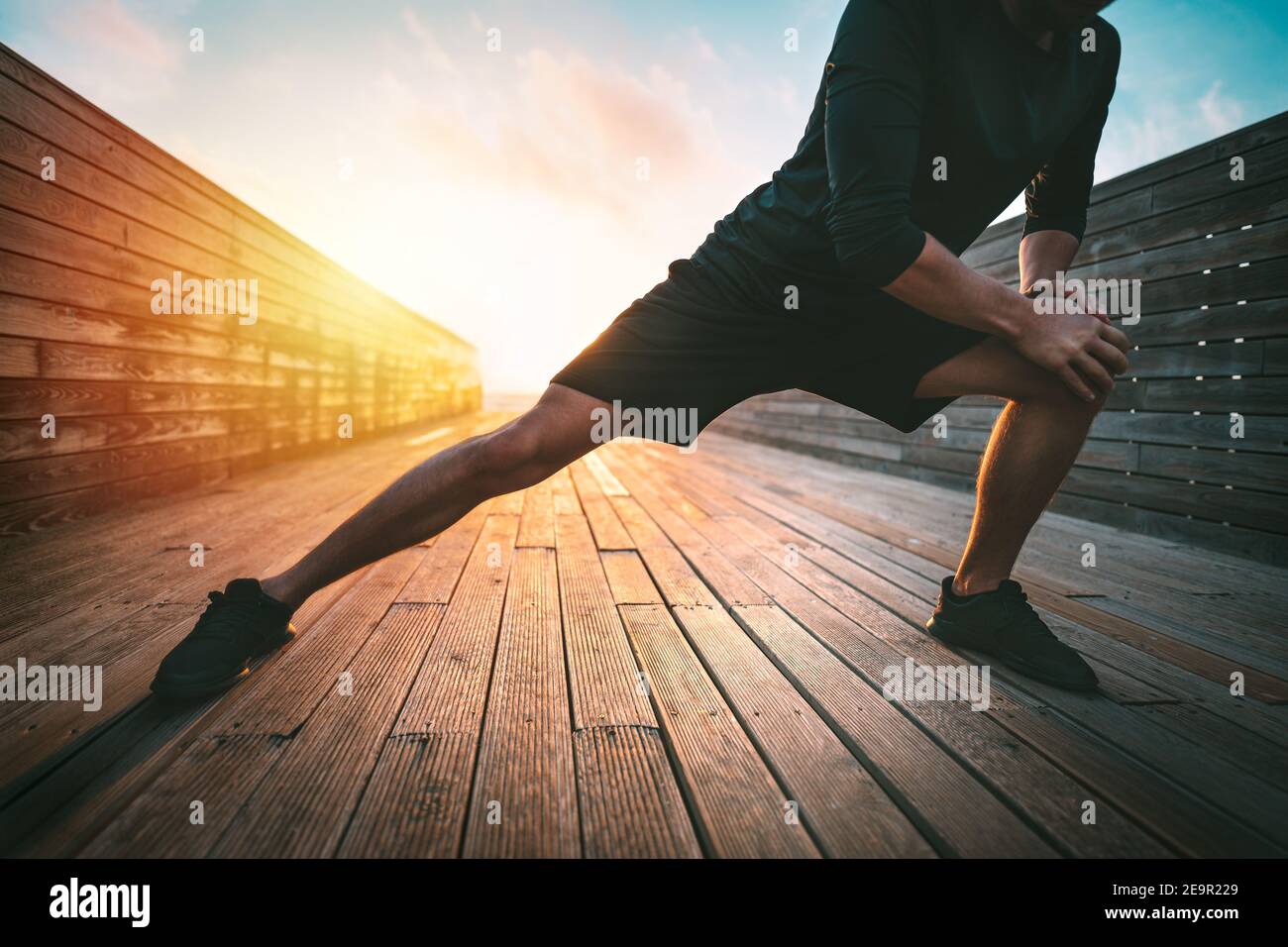 Fitness-Mann Stretching Beine vor dem Training im Freien. Aufwärmen vor dem Laufen. Sport und gesunder Lebensstil. Stockfoto