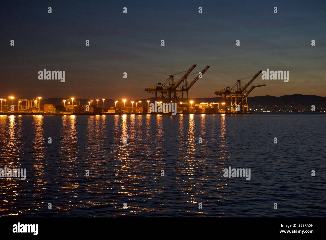 Hafen von Oakland bei Sonnenuntergang. Intermodale Container und Krane in der Bucht von San Francisco. Internationaler Handel und Handel. Stockfoto