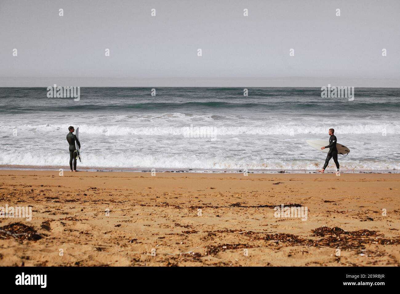 Zwei Surfer blicken auf die Wellen des Südlichen Ozeans bei Moyji oder Point Ritchie in Warrnambool, Southwest Victoria, Australien Stockfoto