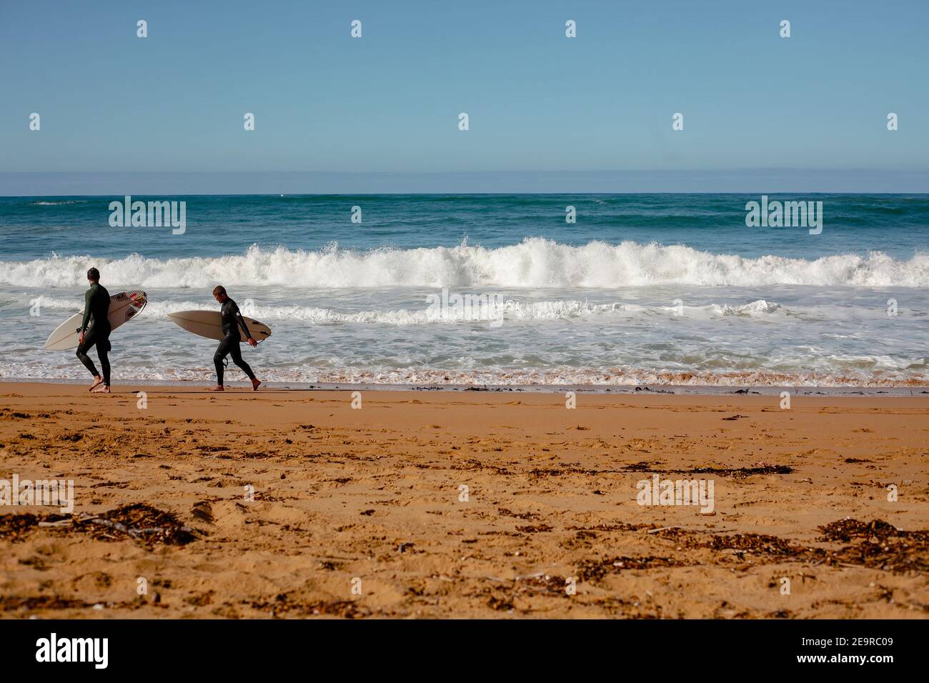 Zwei Surfer blicken auf die Wellen des Südlichen Ozeans bei Moyji oder Point Ritchie in Warrnambool, Southwest Victoria, Australien Stockfoto