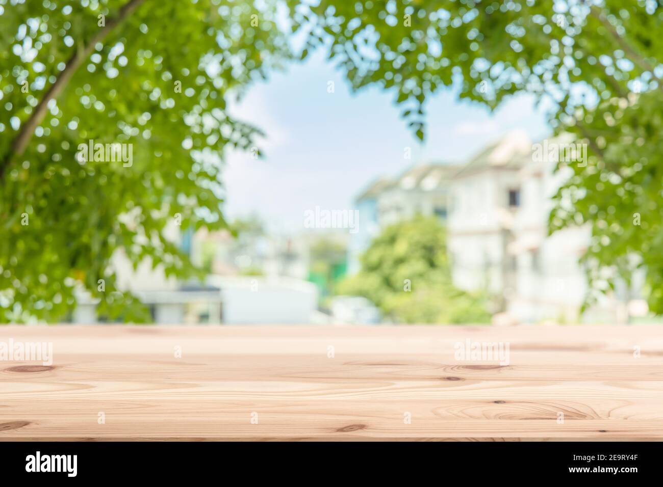 Grüne Stadt Haus Öko Gemeinschaft verwischen Hintergrund mit Holztisch Vordergrund Raum für Produkte Werbevorlage Stockfoto