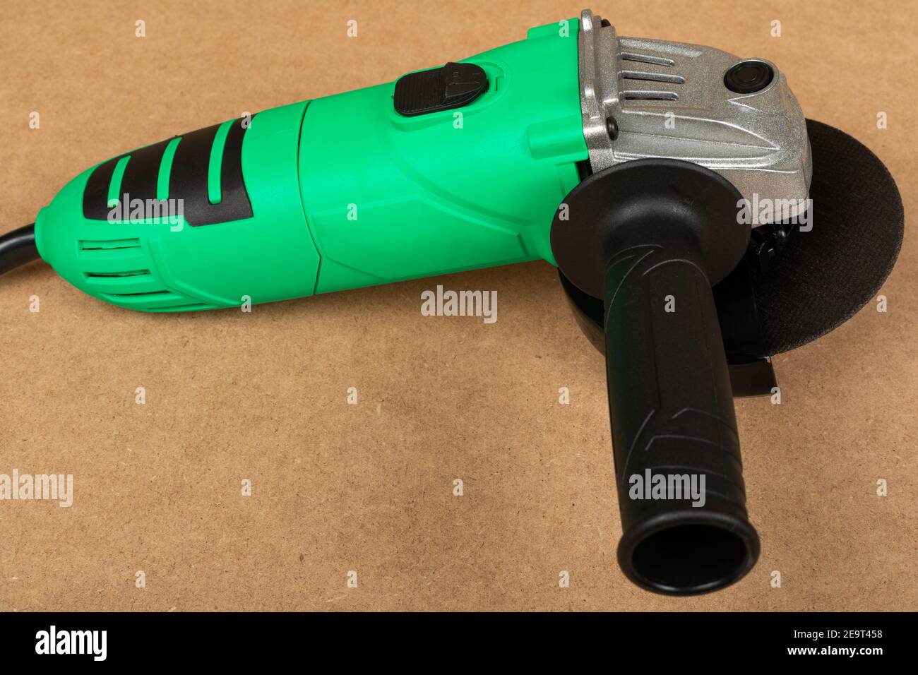 Bild eines grünen Winkelschleifers auf einem Holzhintergrund Stockfoto