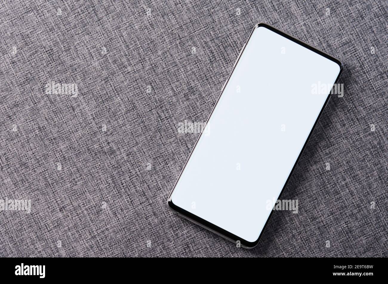 Weißer Bildschirm auf Smartphone in grau weichen Stoff Hintergrund Stockfoto