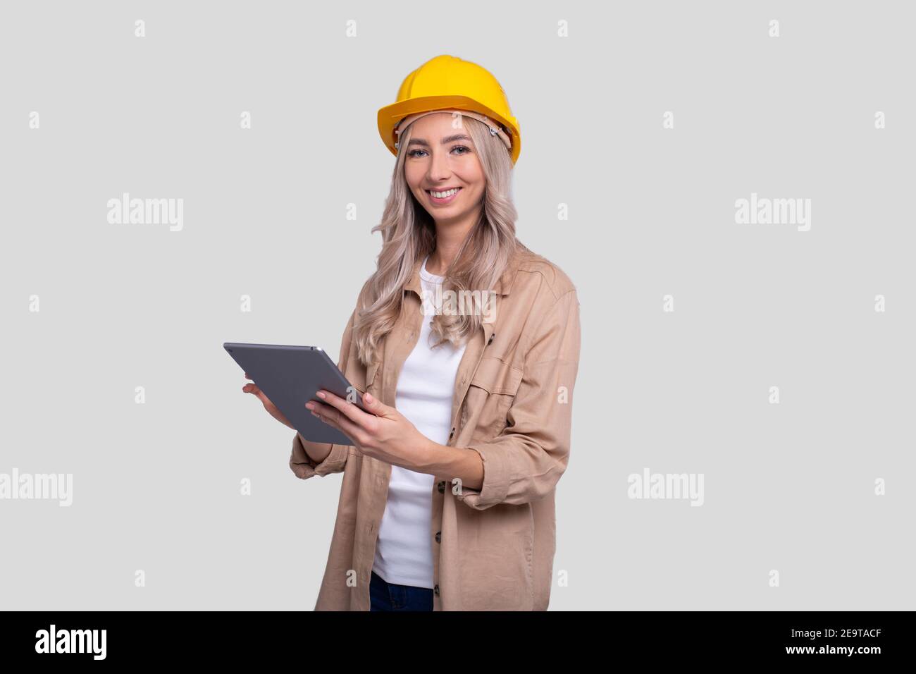 Mädchen Bauarbeiter Smilling Halten Tablet Beobachten Front Isoliert. Mädchen, die mit Tablet arbeiten. Moderne Konstruktion, Technik, Arbeitskonzept Stockfoto