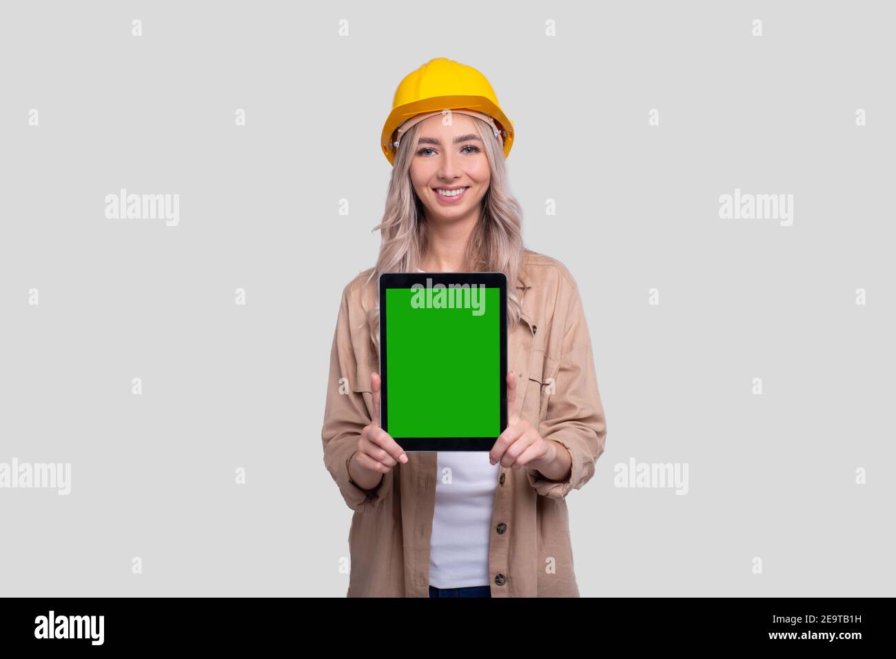 Mädchen Bauarbeiter Zeigt Tablet Green Screen Isoliert Stehen. Kommecial, Shopping, Werbung, Arbeit, Baukonzept Stockfoto