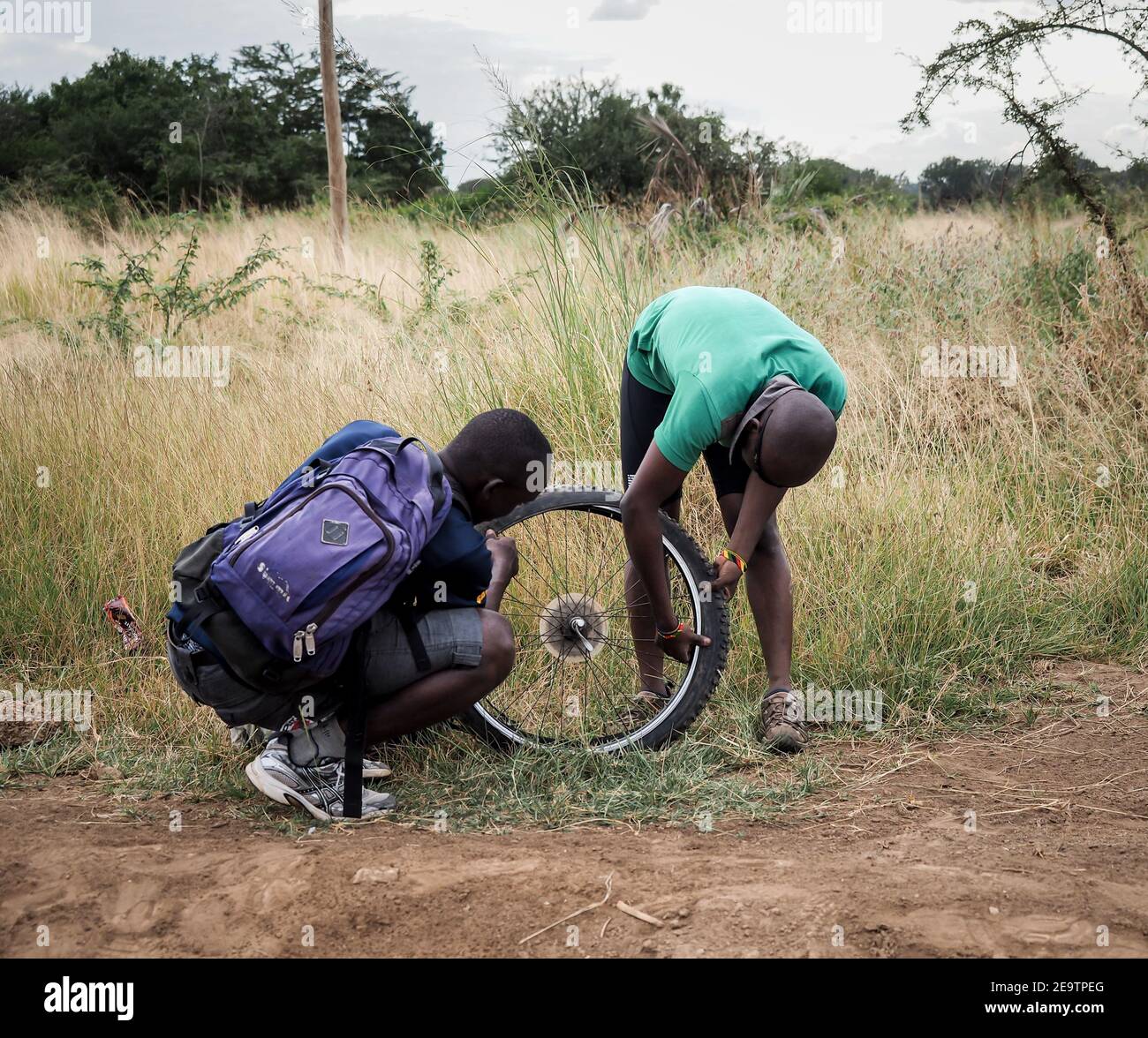 Zwei afrikanische Männer reparieren in tansania einen flachen Fahrradreifen Stockfoto
