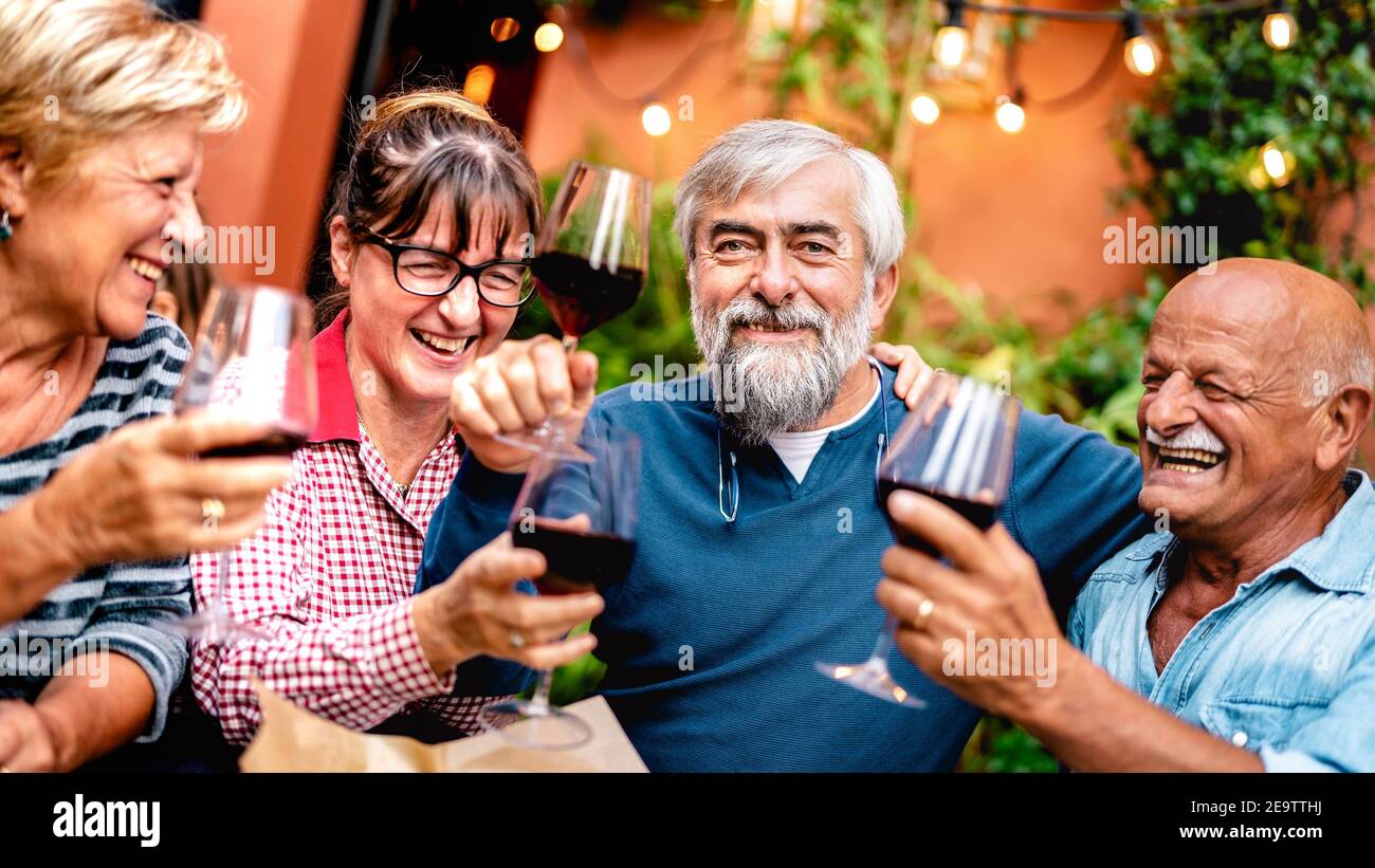 Glückliche ältere Freunde, die beim Abendessen gerne Rotwein toasten Party - Rentner trinken im Restaurant zusammen - Essen Freundschaftskonzept Stockfoto