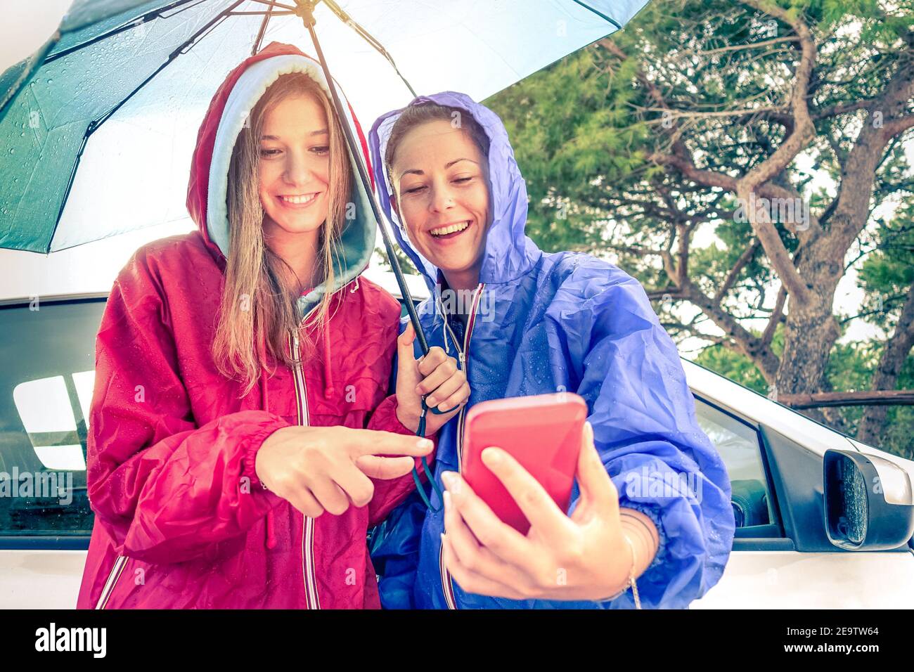 Frauen beste Freunde genießen mit Smartphone mit Sonne kommt heraus Nach dem Regen - Autotour mit jungen Freundinnen Spaß zusammen - Vintage Filter Stockfoto