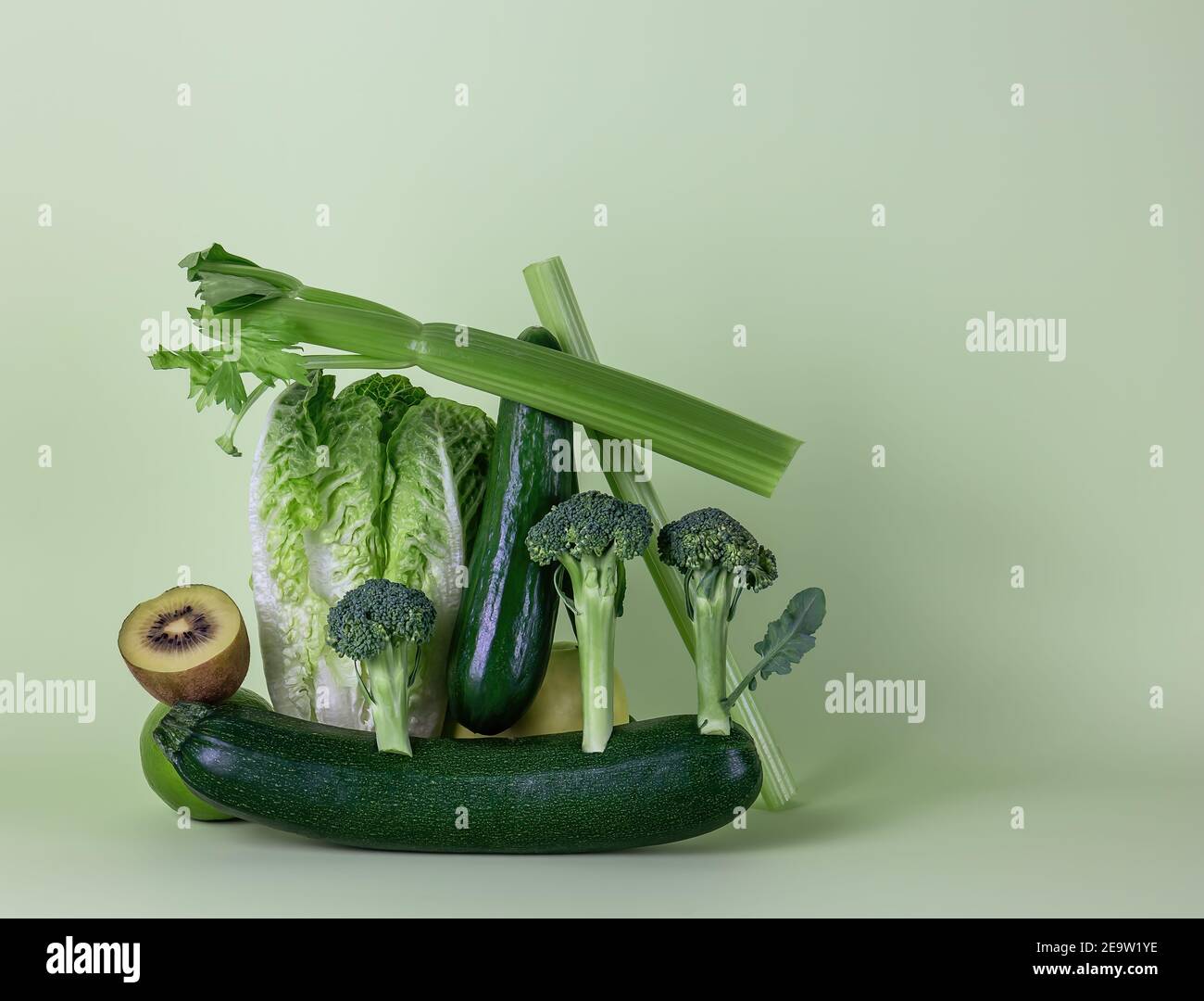 Frisches grünes Gemüse und Obst auf grünem Hintergrund. Gleichgewicht schwimmende Lebensmittelbalance. Stockfoto