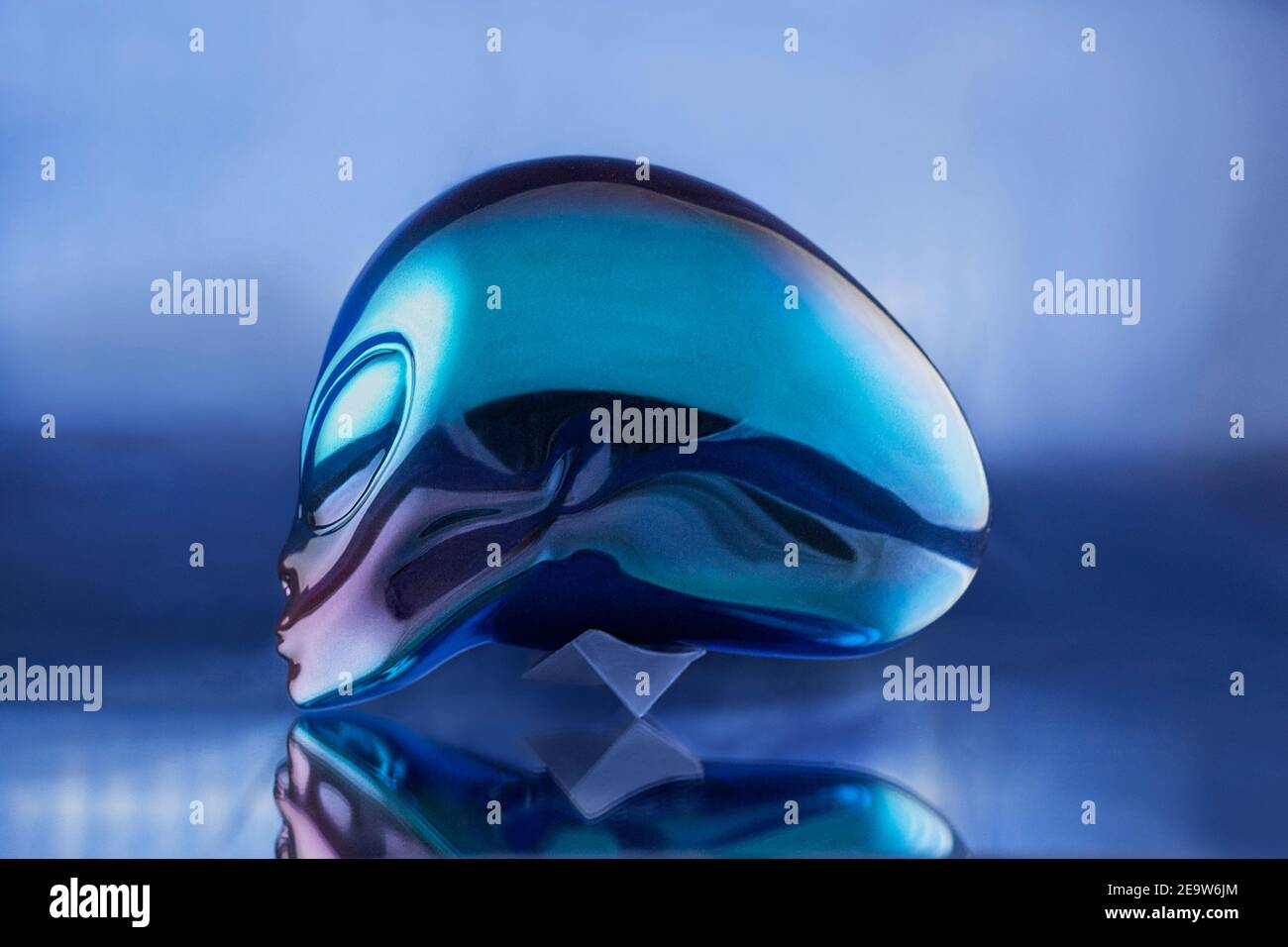 Alien Metall Kopf Statue auf blauem Hintergrund auf dem Tisch Stockfoto