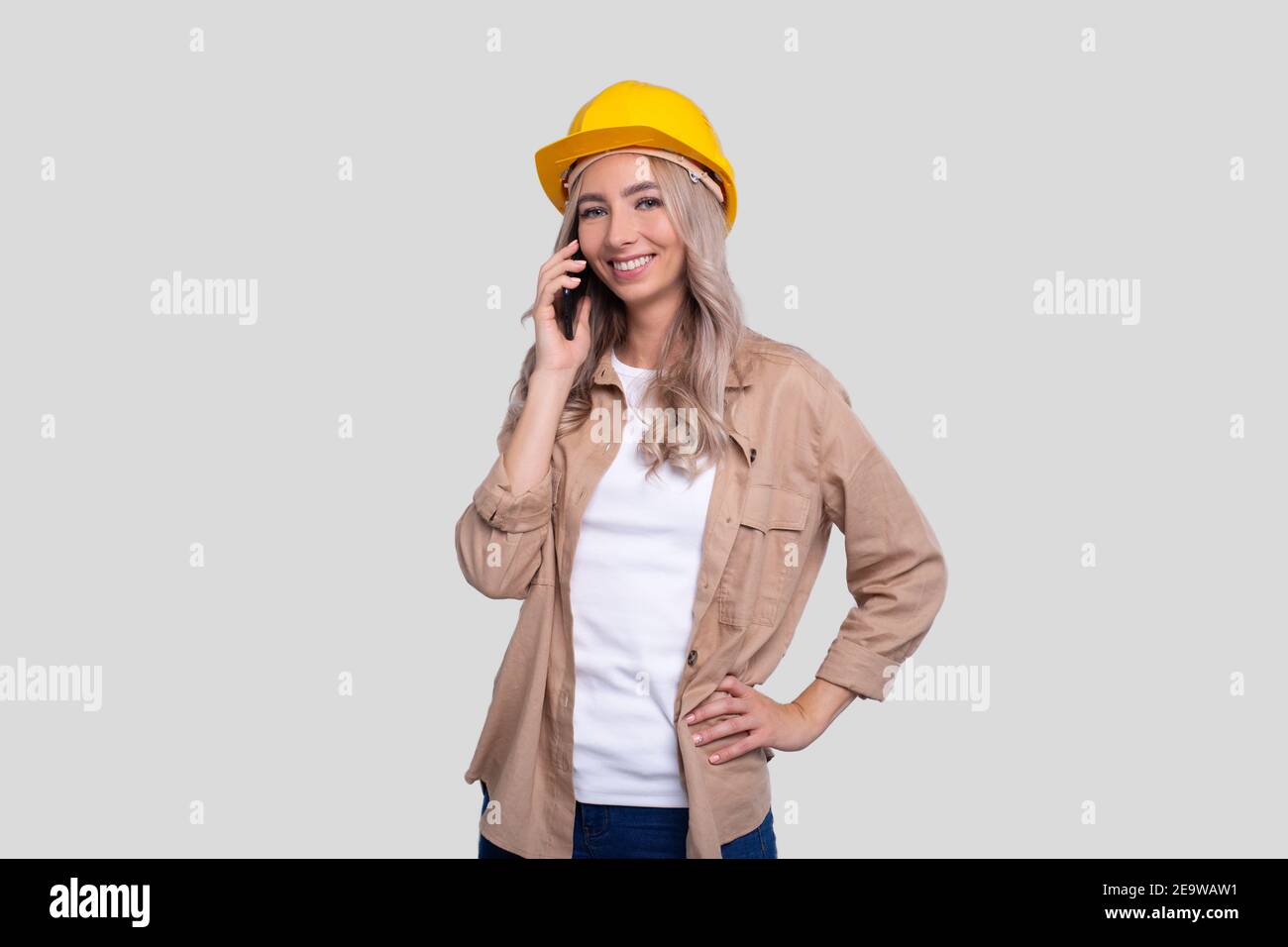 Mädchen Bauarbeiter smilling Gespräch am Telefon beobachten Front isoliert. Mädchen, Die Arbeitet. Moderne Konstruktion, Technik, Arbeitskonzept Stockfoto