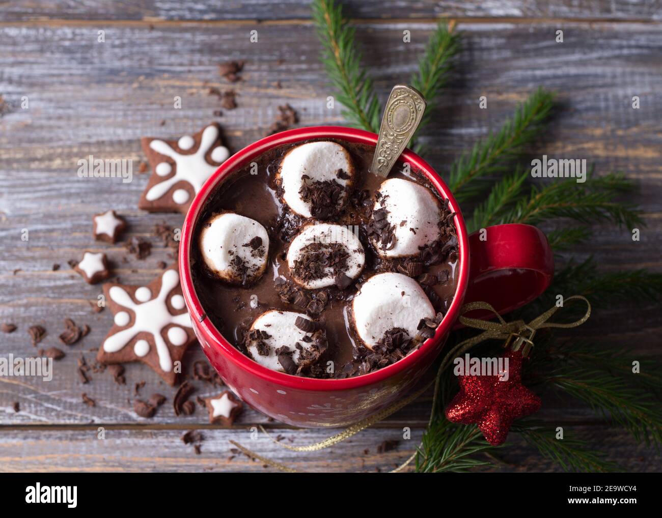 Heiße Schokolade mit Marshmallows und geriebener Schokolade in einem roten Becher mit Keksen und weihnachtsbaum auf einem Holztisch, rustikaler Stil. Köstliche weihnachten Stockfoto