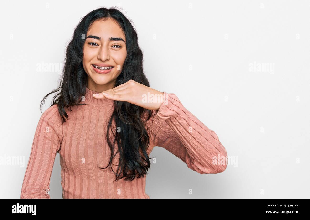 Hispanic Teenager Mädchen mit Zahnspangen tragen lässige Kleidung gesturing mit Händen zeigt große und große Größe Zeichen, Maßnahme Symbol. Lächelnd suchen Stockfoto