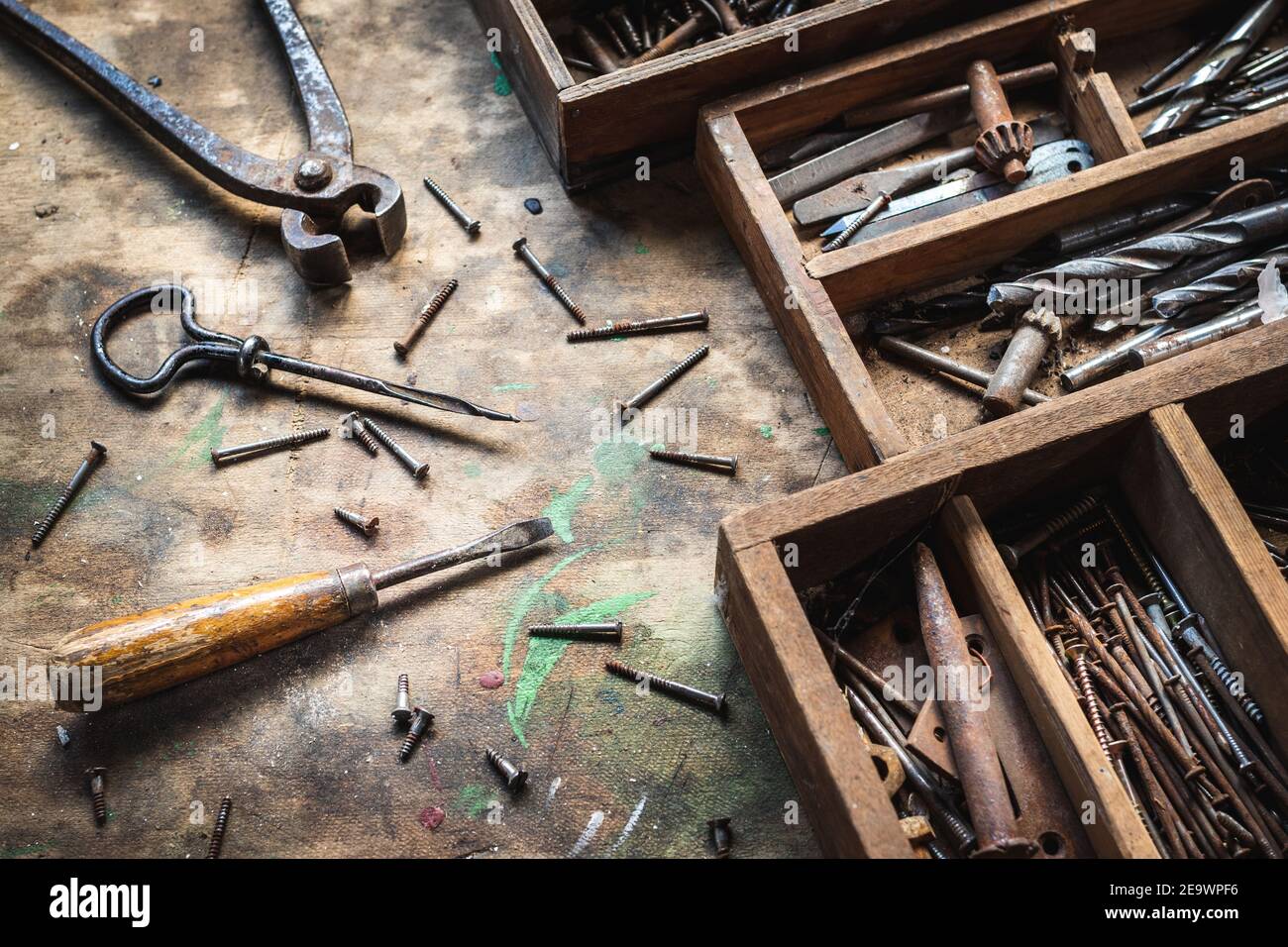 Vintage-Arbeitswerkzeug auf Holztisch in der Werkstatt. Zimmerei Industrieausrüstung und Werkzeugkasten. Unordentliche Schraubendreher, Zange, Handbohrer und Nagel und Schrauben Stockfoto