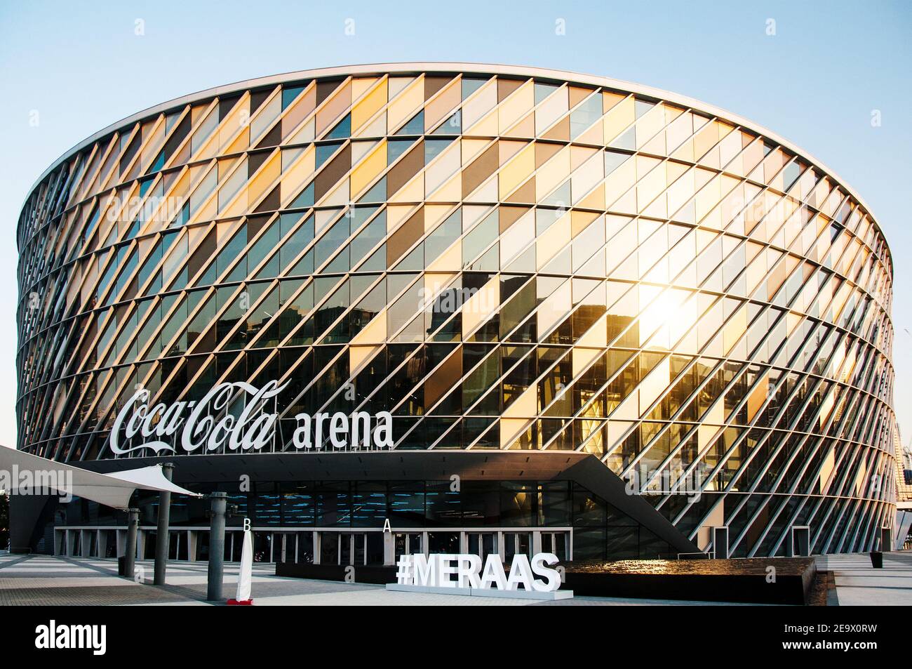 Stadion der Coca-Cola Dubai Arena bei Sonnenuntergang. Das goldene Licht reflektiert das Stadion mit dem Burj Kalifa im Hintergrund, das sich im luxuriösen City Walk-Bereich befindet Stockfoto