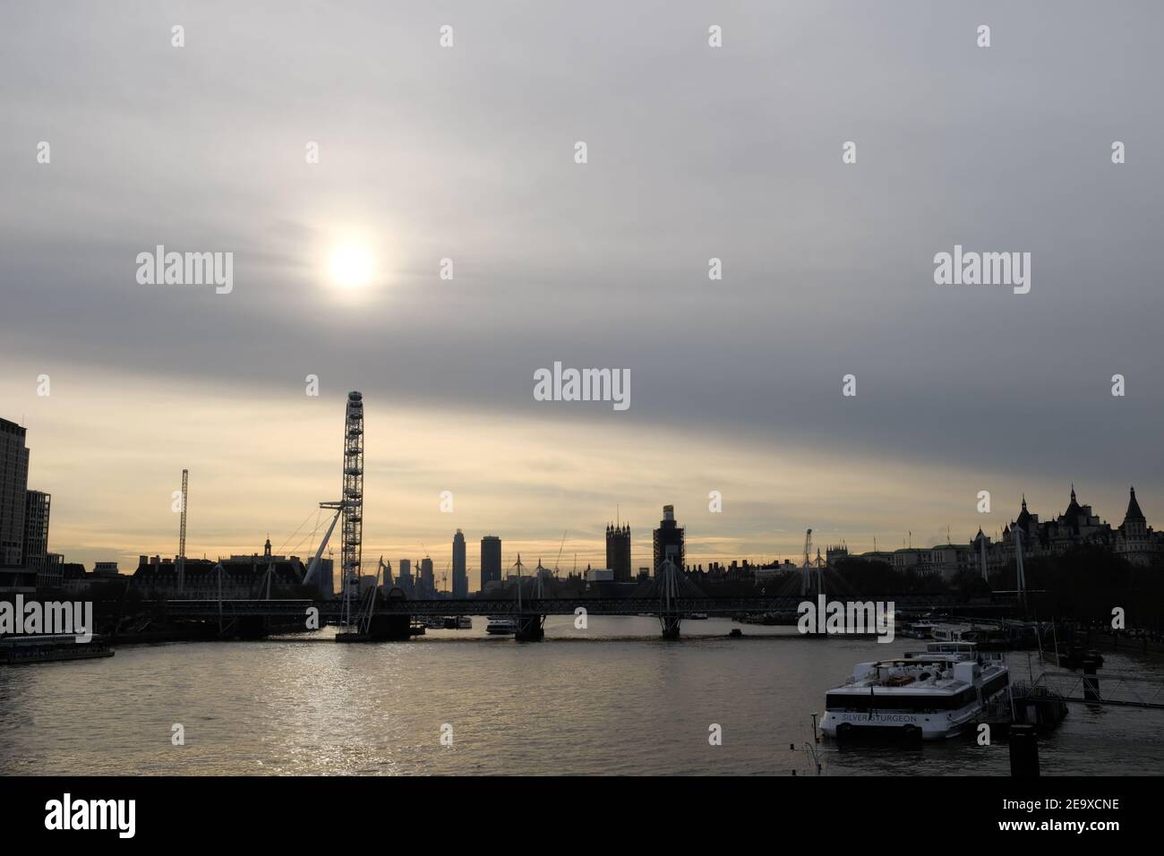 LONDON - DEZEMBER 2018: Spätabendaufnahme von Waterloo Bride mit Blick auf Westminster. Die Sonne untergeht durch den wolkigen Himmel Stockfoto