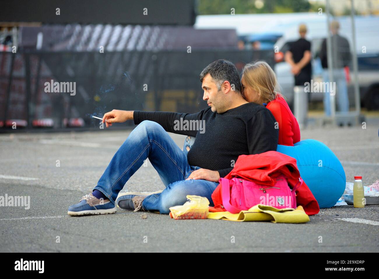 Mann sitzt auf einem Sitzsack, raucht eine Zigarette, Frau hinter dem Hals küsst. Loungebereich, entspannend Stockfoto