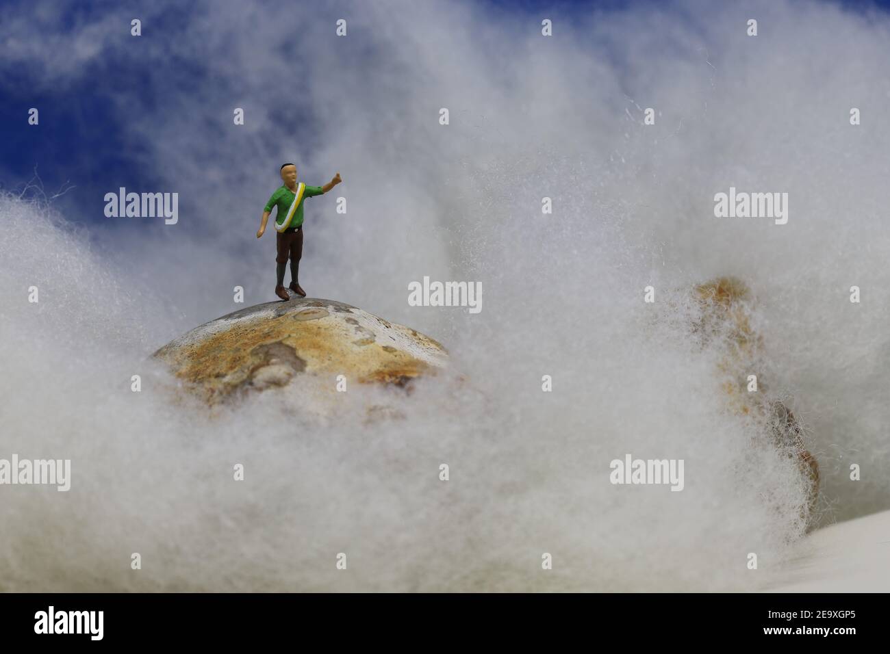 Model-Kletterer am Gipfel über den Wolken. Stockfoto
