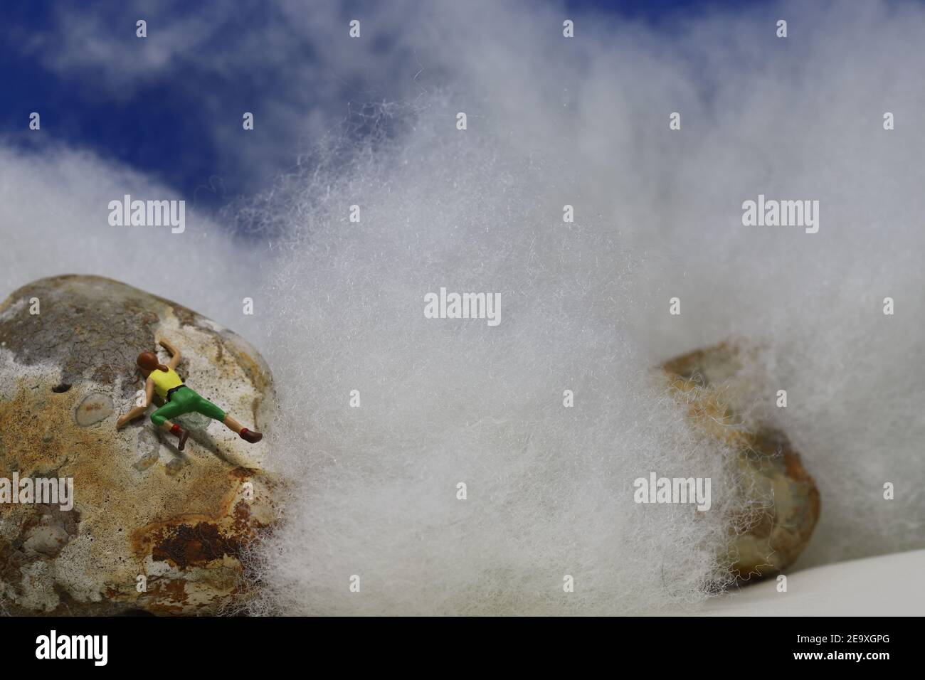 Model-Kletterer am Gipfel über den Wolken. Stockfoto