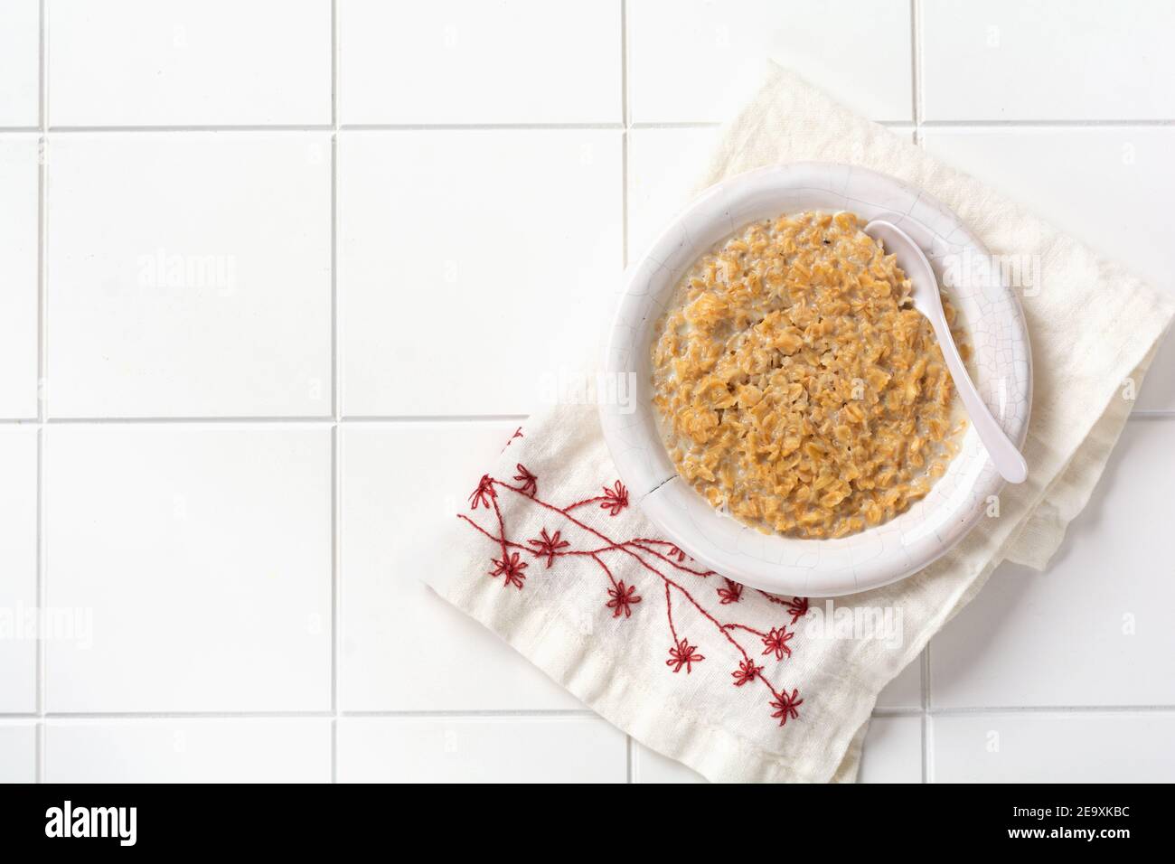 Einfacher Haferbrei Haferbrei mit Erdbeeren in einem weißen Teller auf einer Leinenserviette. Frühstück Gesundheit Essen Konzept. Draufsicht. Stockfoto