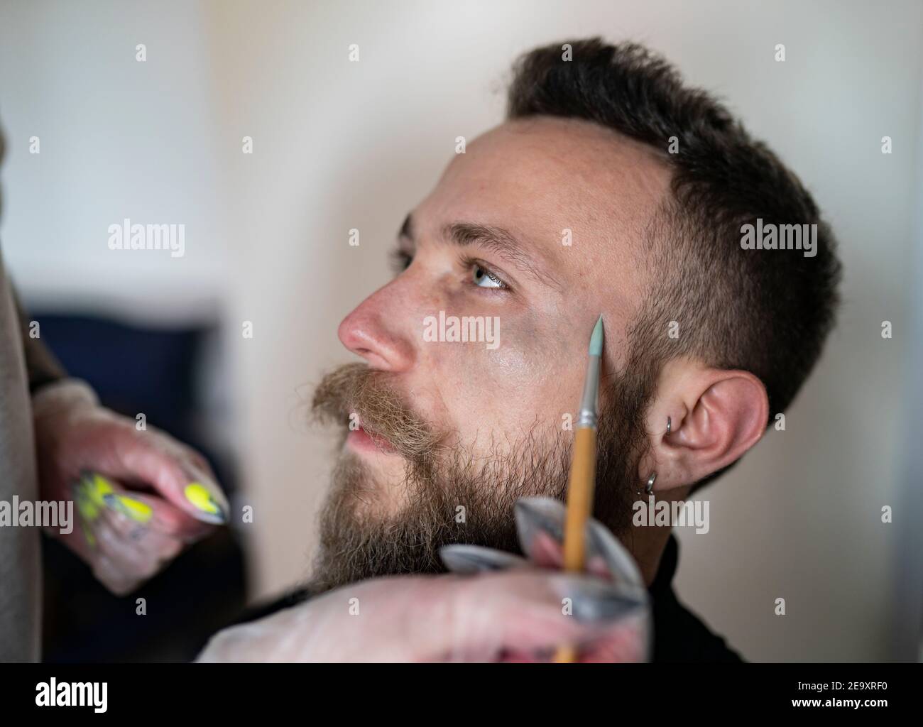 Nahaufnahme eines unkenntlichen Make-up-Künstlers, der ein Make-up aufsetzt Das Gesicht des Hipster-Mannes Stockfoto