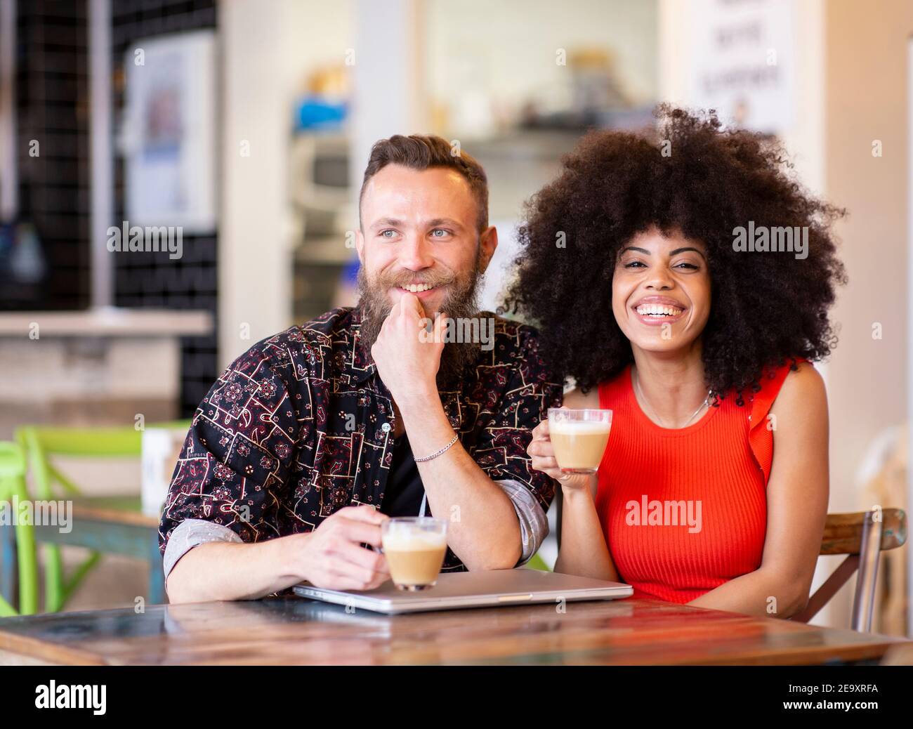 Ein zufriedenes multiethnisches Paar, das im Café sitzt und Zeit zusammen verbringt Während Sie das Wochenende genießen und die Kamera betrachten Stockfoto