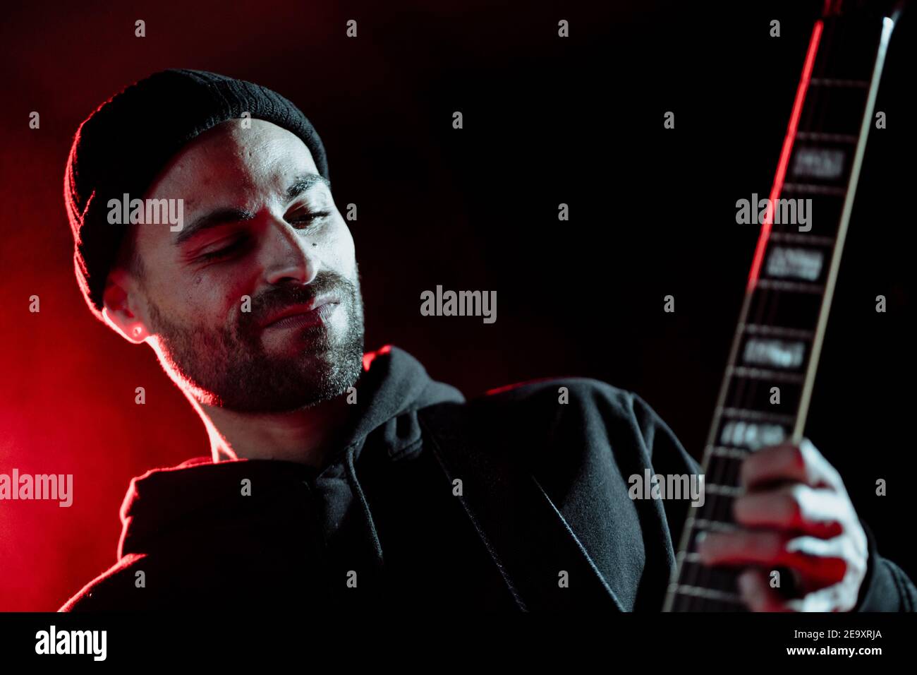 Niedriger Winkel der Rock-Gitarrist spielt E-Gitarre während der Durchführung Im dunklen Studio mit rotem Licht Stockfoto