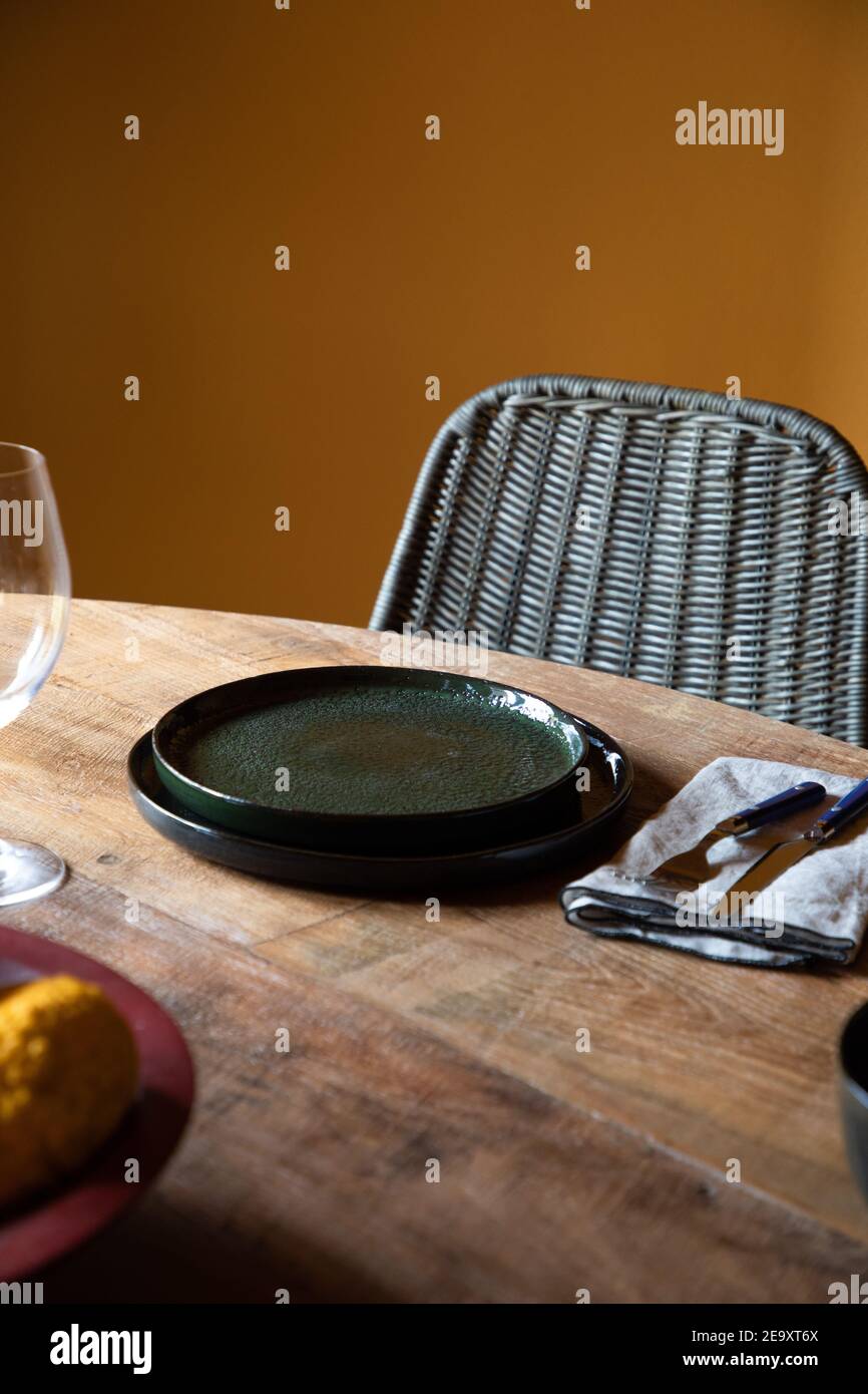 Von oben Holztisch mit Keramikplatten und Besteck Auf Serviette in der Nähe von Weinglas im Restaurant Stockfoto