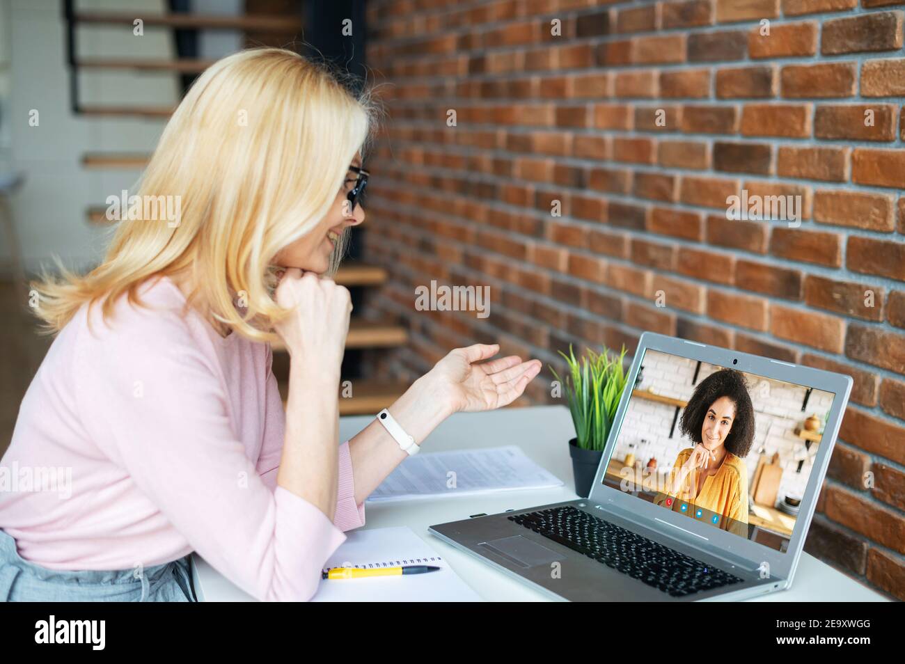 Videoanruf-Konzept. Zwei Kolleginnen sprechen online über eine Videoverbindung auf dem Laptop. Ein Lehrer mittleren Alters hat virtuelle Konferenz mit einem Schüler Stockfoto