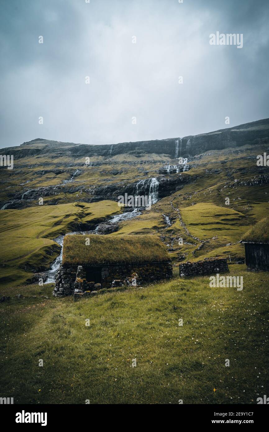 Wasserfälle in der Ortschaft Saksun auf den Färöer Inseln. Keine Menschen um, traditionelle Häuser aus Stein. Stockfoto