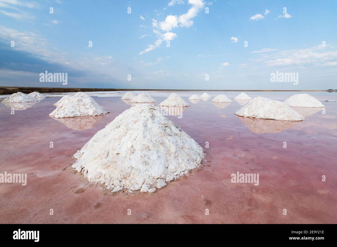 Totes Meersalz Ebenen mit den Pyramiden von ausgegrabenem Salz. Wasser mit rosa Algen gefärbt. Stockfoto