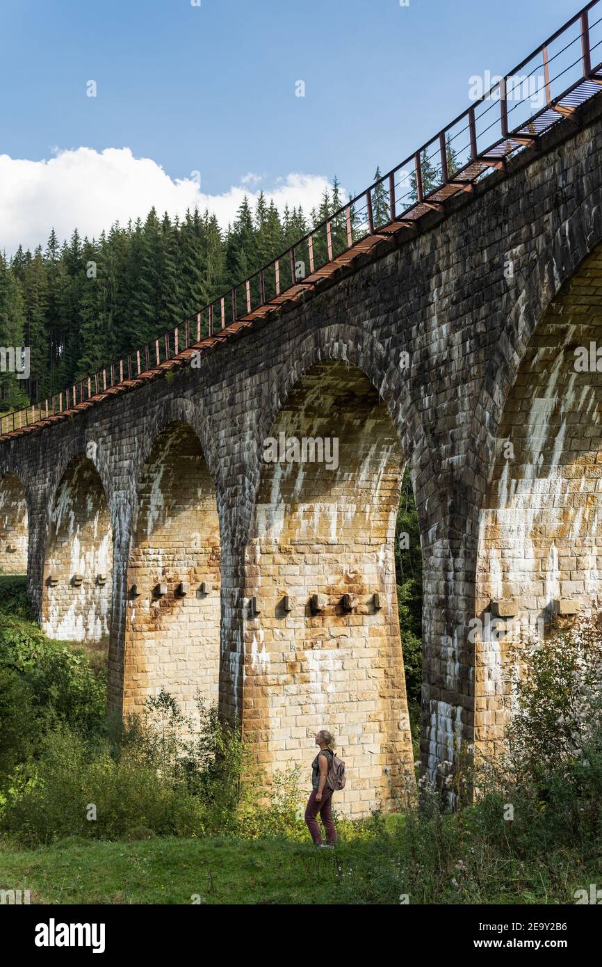 Frau unter alten Eisenbahnviadukt in Karpaten Dorf Worokhta, Ukraine. Stockfoto