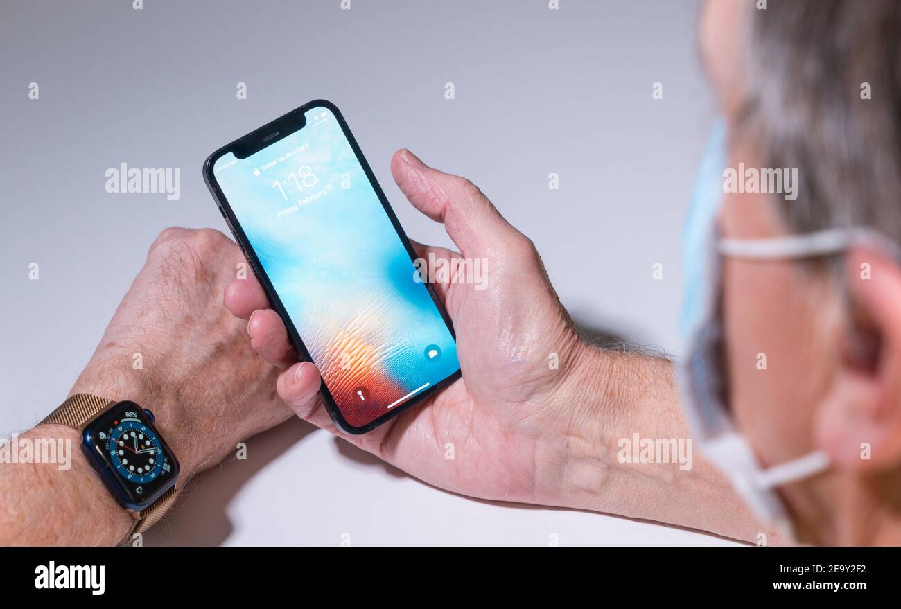 Morgantown, WV - 5. Februar 2021: Apple iphone und Uhr verwenden Gesichtserkennung, um das Telefon zu öffnen, auch wenn Sie eine Gesichtsmaske tragen Stockfoto