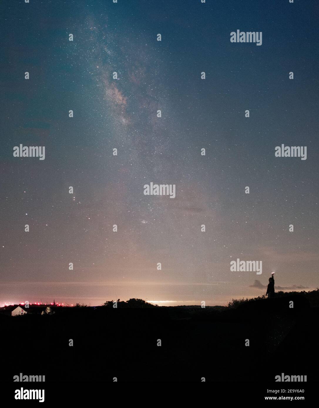 Mann hält eine Taschenlampe hoch und beleuchtet die Nacht Himmel mit der Milchstraße im Hintergrund Stockfoto