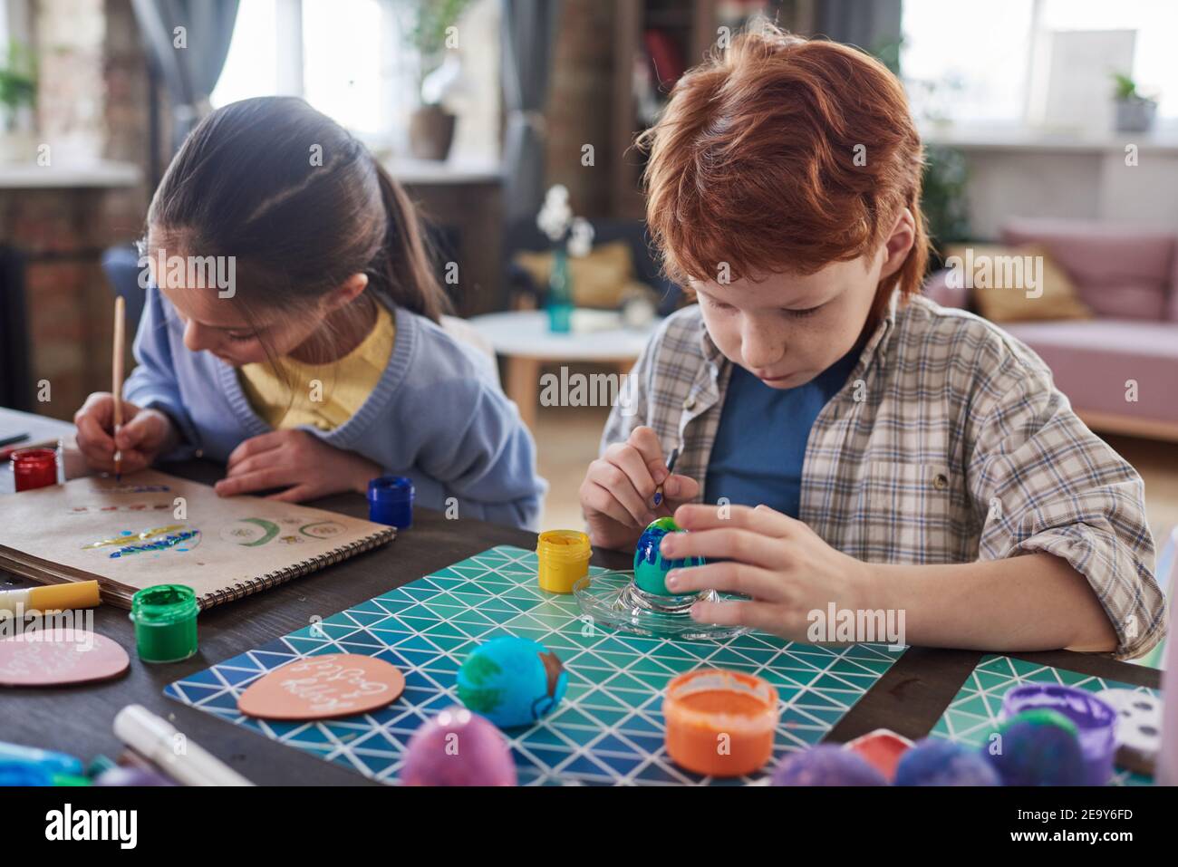 Zwei Kinder sitzen am Tisch mit Farben und Malerei Mit Farbbürsten Stockfoto