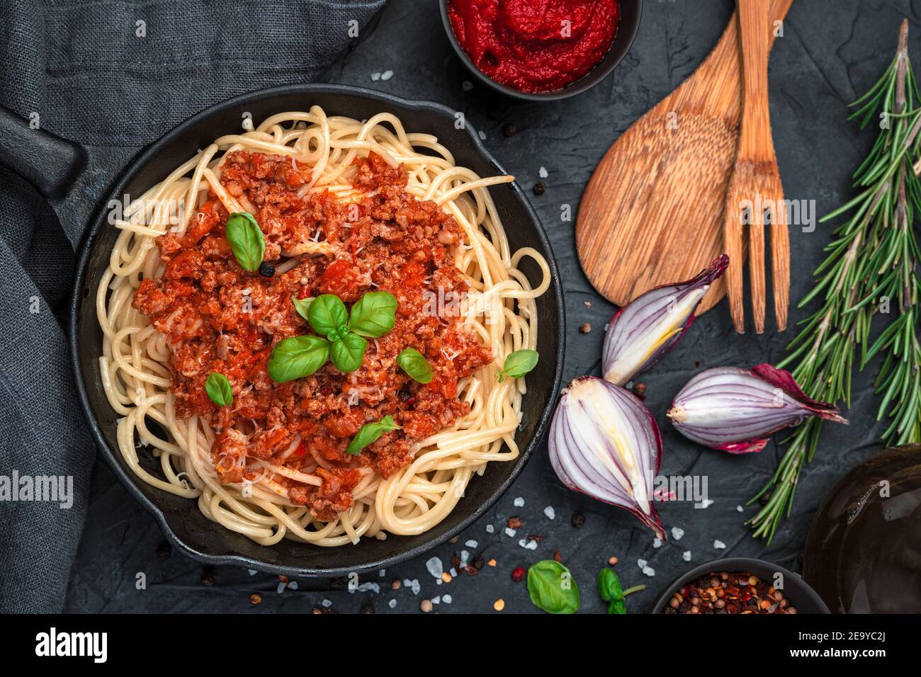 Spaghetti und Tomatensauce mit Hackfleisch und frischem Basilikum auf schwarzem Hintergrund. Draufsicht, horizontal. Das Konzept der kulinarischen Hintergründe. Stockfoto