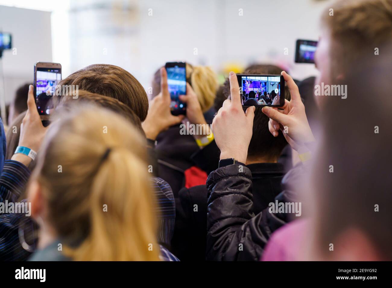 Personen, die während einer Präsentationsveranstaltung Videos auf ihrem Telefon aufzeichnen Stockfoto