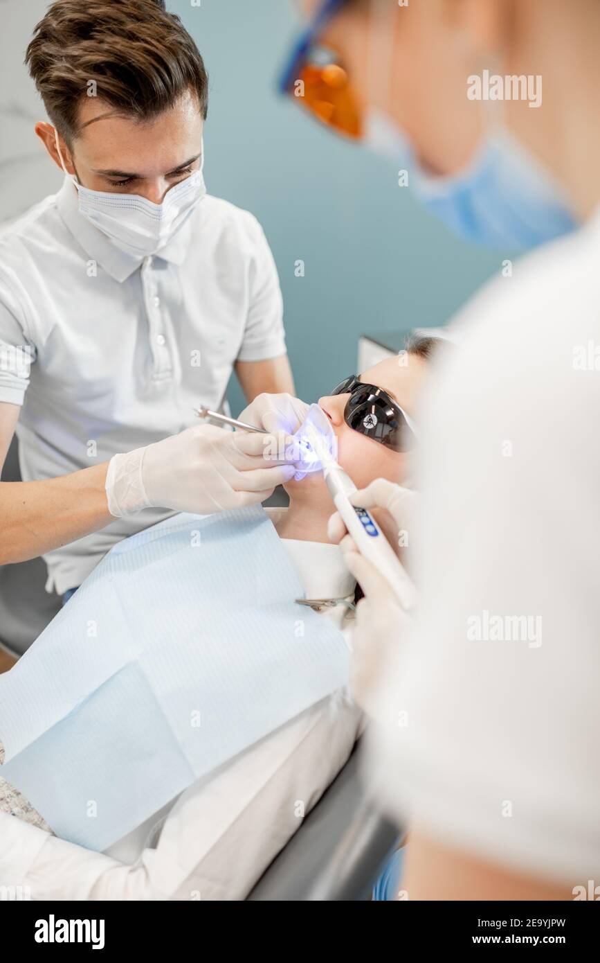 Männlicher Zahnarzt und Assistent mit zahnheilenden Licht Stockfoto