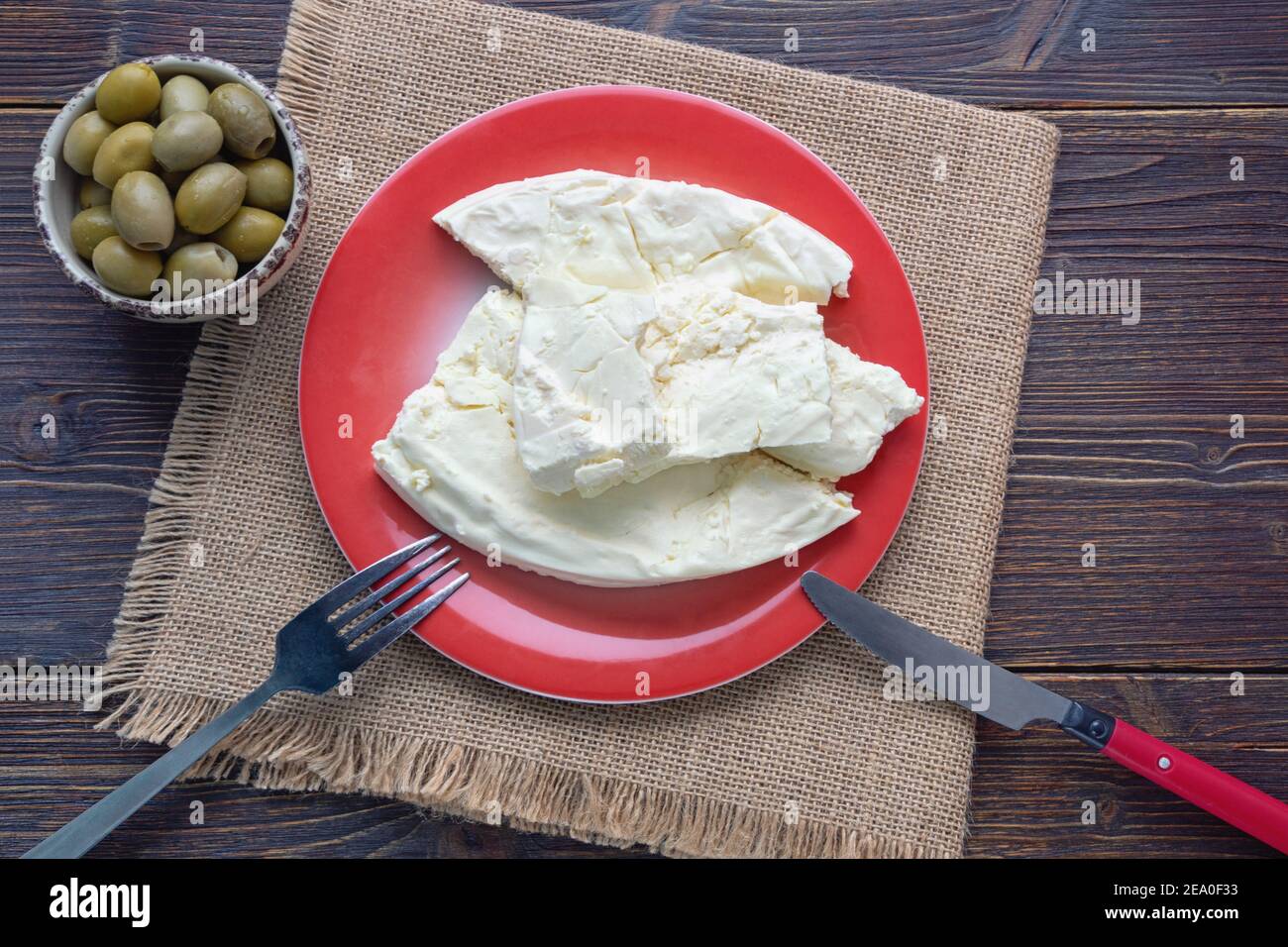 Balkan-Küche. Montenegro. Pljevaljski Cheese - lokaler Weichkäse in roter Platte auf dunklen rustikalen Tisch. Speicherplatz kopieren Stockfoto