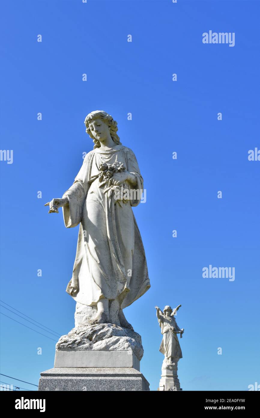 Engelstatuen in einem kalifornischen katholischen öffentlichen Friedhof mit offenem Himmel, der klar ist, von vor dem Weltkrieg 2 Bestattungen für lokale Familien und Kopie Stockfoto
