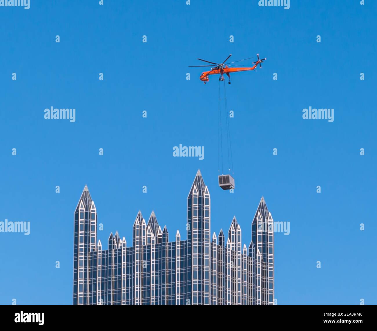 Ein Sky-Kran-Hubschrauber liefert eine Klimaanlage an die Spitze des PPG-Gebäudes in der Innenstadt von Pittsburgh, Pennsylvania, USA Stockfoto