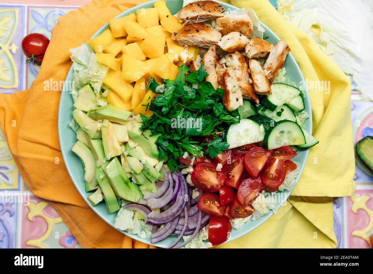 Chicken Paleo Diät Salatschüssel mit Fleisch, Yelloe Mango, Avocado und frischen Gemüse Zutaten auf bunten Hintergrund Draufsicht. Stockfoto